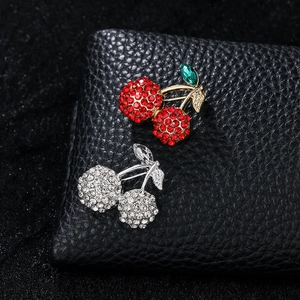 Macro shot of sparkling red and crystal cherry brooches with rhinestones on black leather