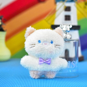 Primo piano di un simpatico ciondolo gatto di peluche bianco con fiocco viola.