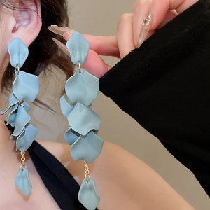 Detailed close-up of long blue acrylic petal tassel earrings worn by a model