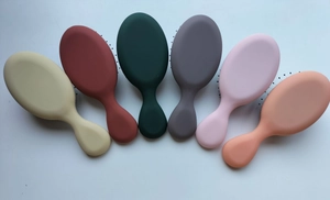 Detailed overhead view of six small colorful oval air cushion hairbrushes in matte finish