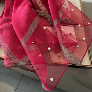 Close-up of red faux silk scarf featuring sheer tulle, gold stripes and pearl bead details