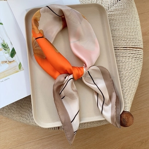 Elegant ginkgo leaf silk scarf with orange and beige panels on a woven background