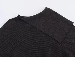 Close-up van zwarte geribbelde gebreide poncho met details van de textuur en de halslijn