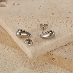 Macro shot of silver teardrop stud earrings on natural stone with polished finish