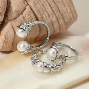 Minimalist stainless steel ring set with shell pearls on a natural wood and shell background