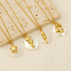 Detail of four gold necklaces featuring white shell pendants with marine life patterns