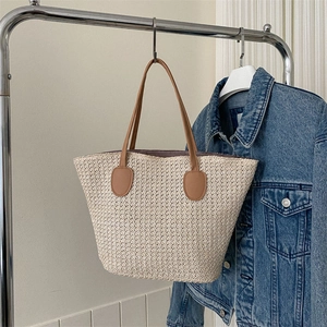 Large beige woven straw tote bag with brown handles and summer beach bucket design