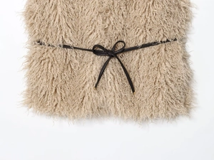 Detailed close-up of beige faux fur texture with a slim black leather bow belt detail
