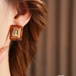 Close-up of vintage amber resin square earrings with central golden crystal stone