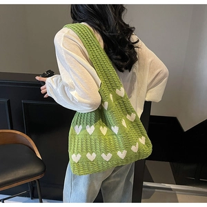 Bolso de punto verde con corazones blancos llevado para mostrar el efecto de caída