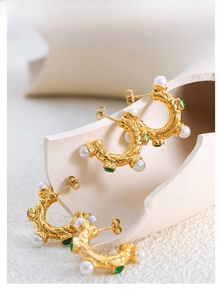 Gros plan sur des boucles d'oreilles C vintage dorées avec perles et pierres vertes