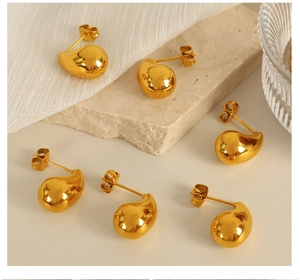 Three pairs of polished gold teardrop stud earrings displayed on a textured stone surface