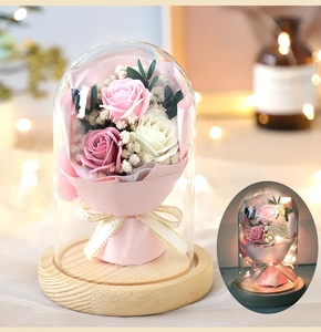 Detail of preserved rose bouquet in glass dome with LED lights and wooden base