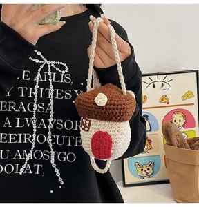 Detail of a handmade knitted crossbody bag featuring a cute mushroom house design