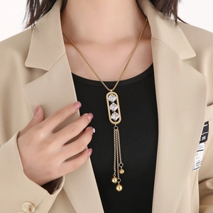 Detail of gold titanium tassel necklace with geometric crystals worn on a black blazer