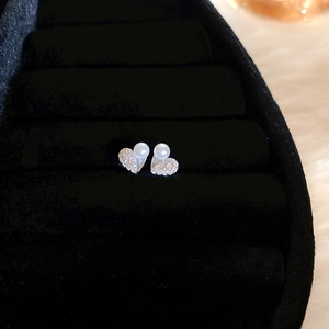 Detailed close-up of heart-shaped pearl stud earrings with zircon inlay in a velvet box