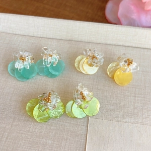 Close-up of shell floral earrings in vibrant turquoise, yellow and green colors