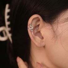 Detailed view of silver snake ear cuff with sparkling stones on a model ear
