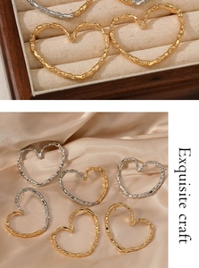 Detailed view of large heart earrings with irregular hammered gold and silver textures