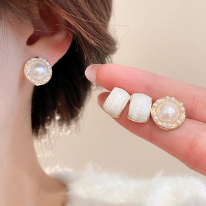 Close-up of elegant pearl stud earrings and cream drip glaze earrings on a model