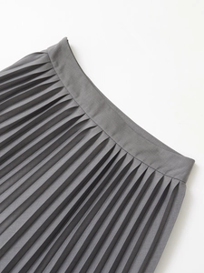 Close-up of high-waisted grey pleated skirt showing fine fabric texture and neat waistband