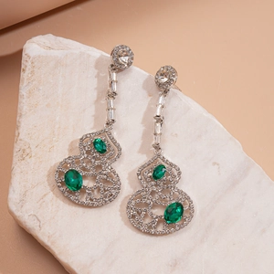 Détail macro de boucles d'oreilles argentées avec pierres vertes sur pierre blanche