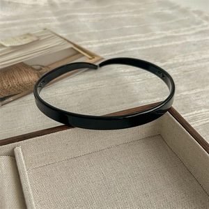 Close-up of a glossy black resin headband displayed in a beige jewelry gift box