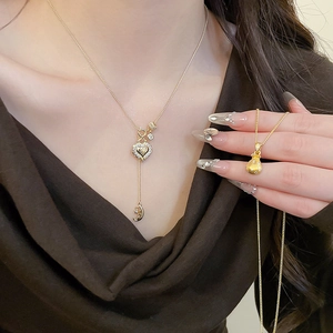 Detailed view of gold necklaces featuring zircon heart and fortune bag pendants on model