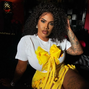 Détail d'un t-shirt blanc avec grand nœud en satin jaune et jupe en dentelle