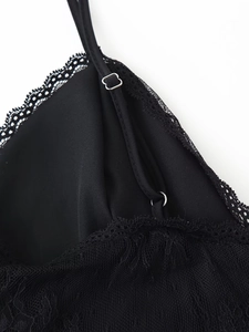 Detail of adjustable straps and lace stitching on a black silk-like V-neck dress