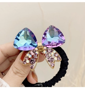 Macro shot of purple crystal bow hair tie with sparkling rhinestones and black elastic