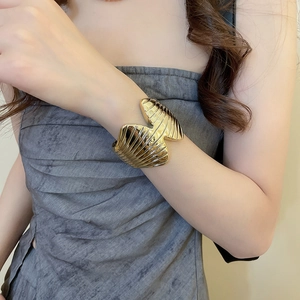 Detailed view of wide gold cuff bracelet featuring textured fan-shaped metal ridges