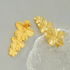 Macro view of gold plated triple flower earrings with brushed metallic petal textures