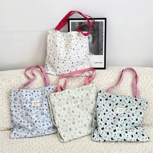 Detail of four colorful quilted tote bags with cat and floral prints and pink handles