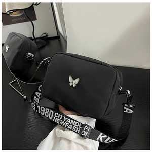 Detail of black nylon crossbody bag with silver butterfly buckle and lettered strap