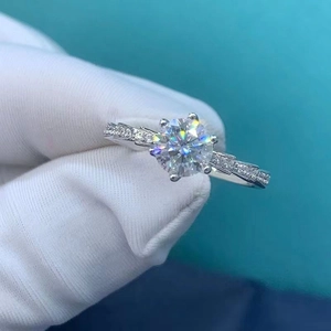 Detail of a silver-toned six-prong moissanite ring with an elegant twisted band design