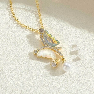 Detailed close-up of a butterfly necklace with blue shell texture, pearls and zircons
