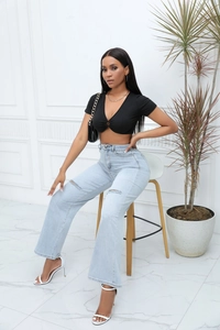 Detail of light blue high-waisted distressed straight jeans with ripped knee design