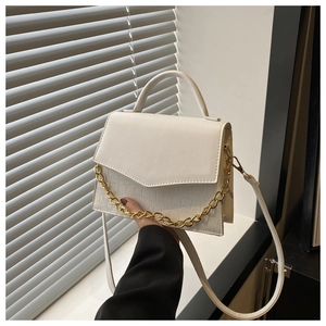 Detail of white crocodile pattern handbag with chunky gold chain decoration and strap