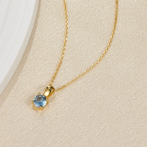 Detail of light blue round-cut birthstone necklace with 4-prong gold setting