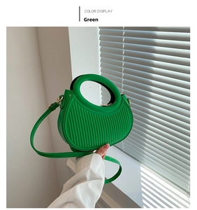 Detail of green crescent bag with vertical pleats and a circular hollow handle