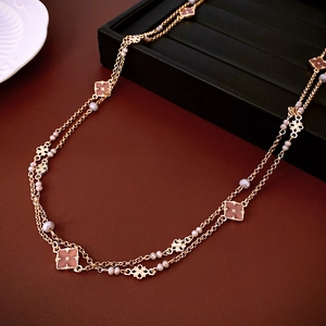 Dettaglio macro della collana con ciondolo a fiore dorato e perle su pelle rossa