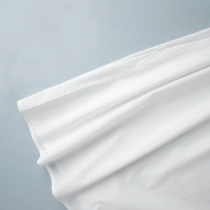 Détail du tissu en coton blanc montrant la texture fine et une couture plate soignée