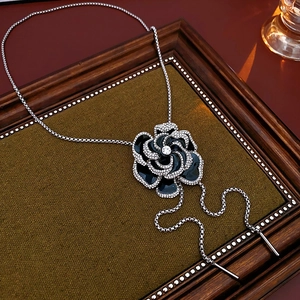 Detail of flower pendant necklace with black enamel petals and crystals on vintage frame