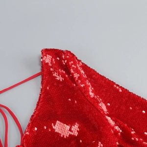 Close-up of red sequin fabric texture and matching thin straps on a backless dress