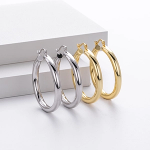 Detailed close-up of high-polish gold and silver hoop earrings on geometric blocks