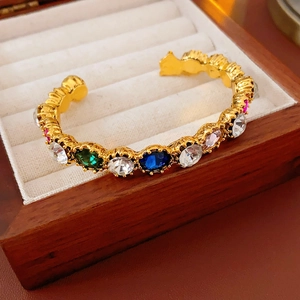 Close-up of vintage gold cuff bracelet featuring multi-colored gemstones on velvet
