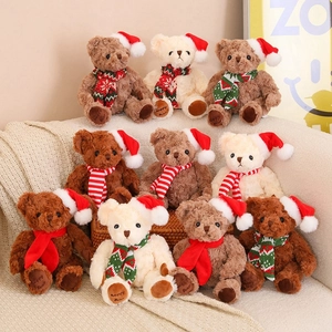 Group of plush Christmas teddy bears in Santa hats and scarves on a soft knit blanket