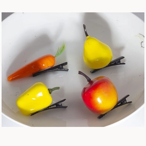 Detail of creative fruit and vegetable hair clips including carrot and pear in a white bowl