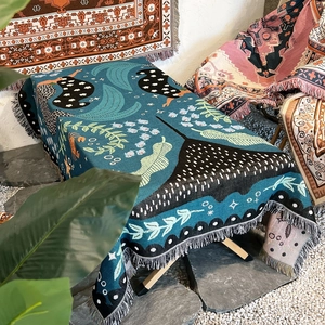 Close-up of Bohemian knit blanket with blue-green ocean patterns and tassel fringe detail